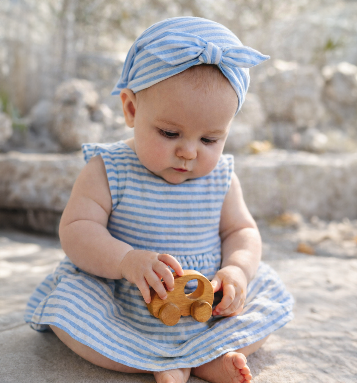 Child holding a natural wood Halo wooden car